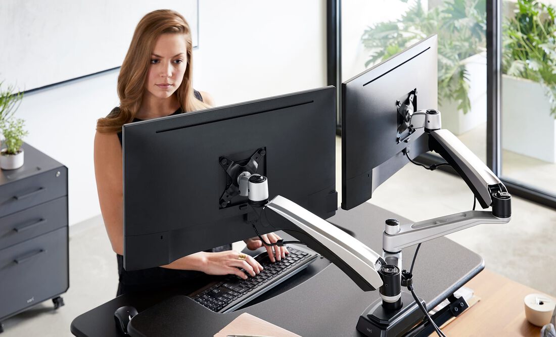 Professional working at dual monitor desk mount setup